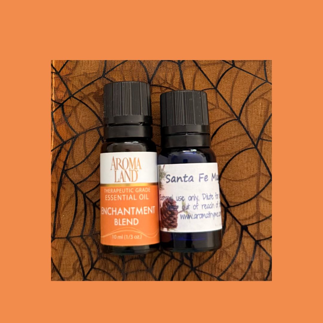 Two essential oil bottles labeled 'Aroma Land' and 'Santa Fe Magic' on a textured  orange background.