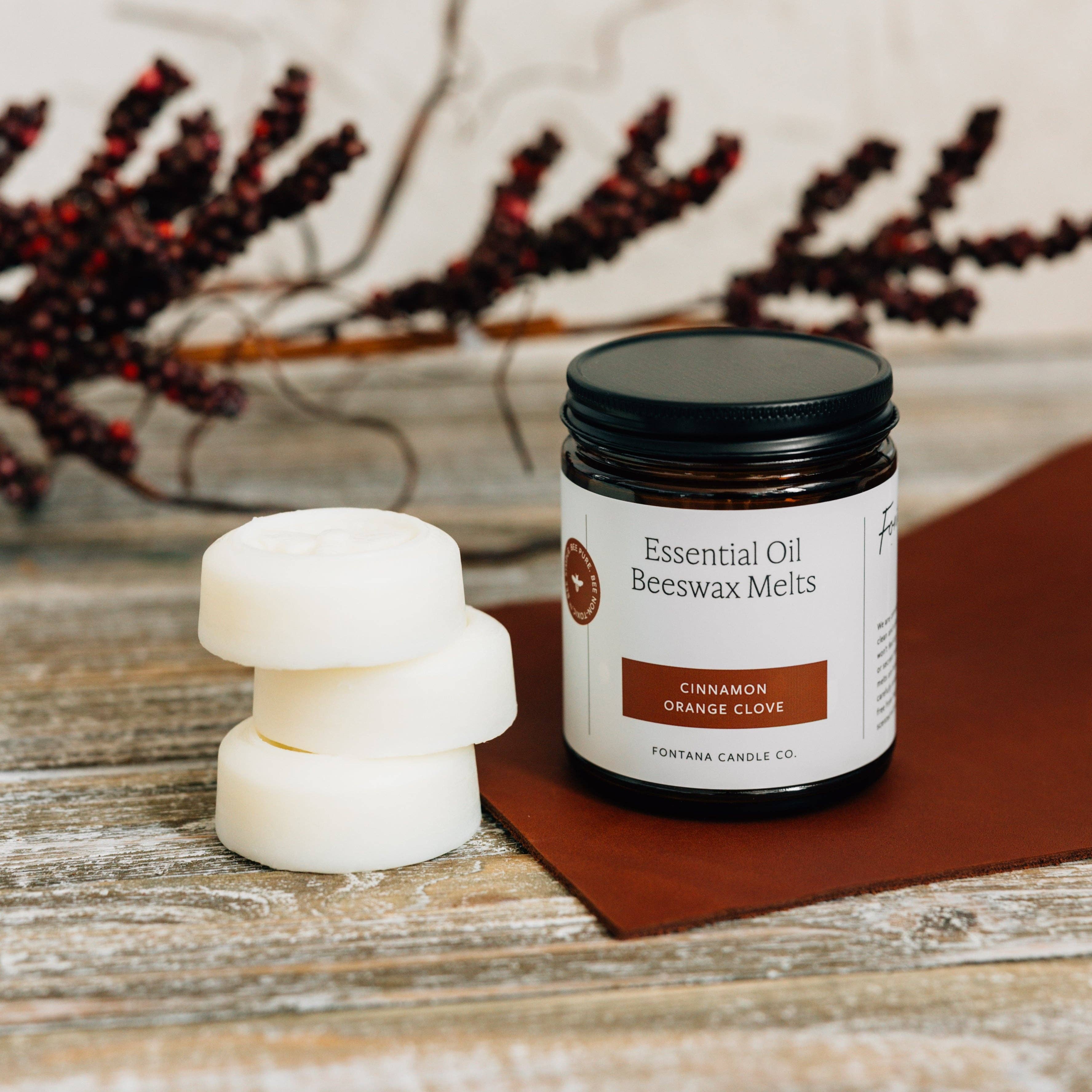 Jar of essential oil beeswax melts with two melts on a wooden surface.